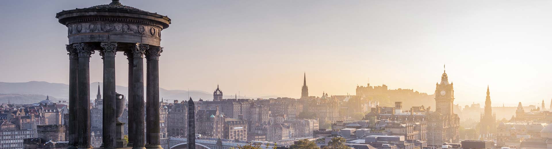 Le soleil perce le ciel sur l'horizon d'Edimbourg, avec le château se silhouettant en arrière-plan.