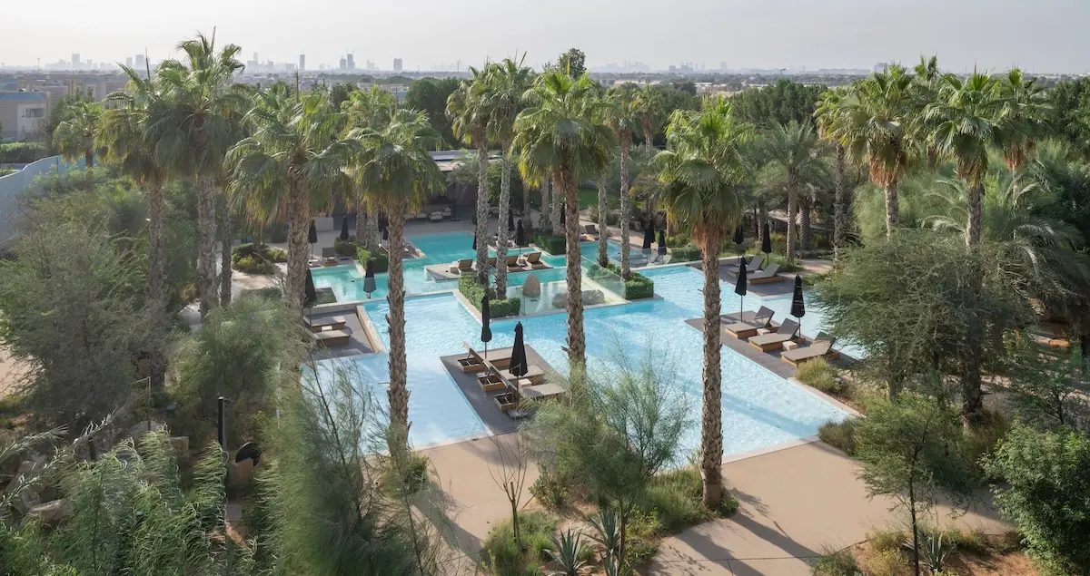 Overheard shot of the swimming pools at Nasab private members club in Dubai, showing pools and palm trees.