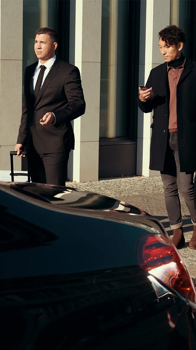 A passenger checks his phone as he is guided by his chauffeur.