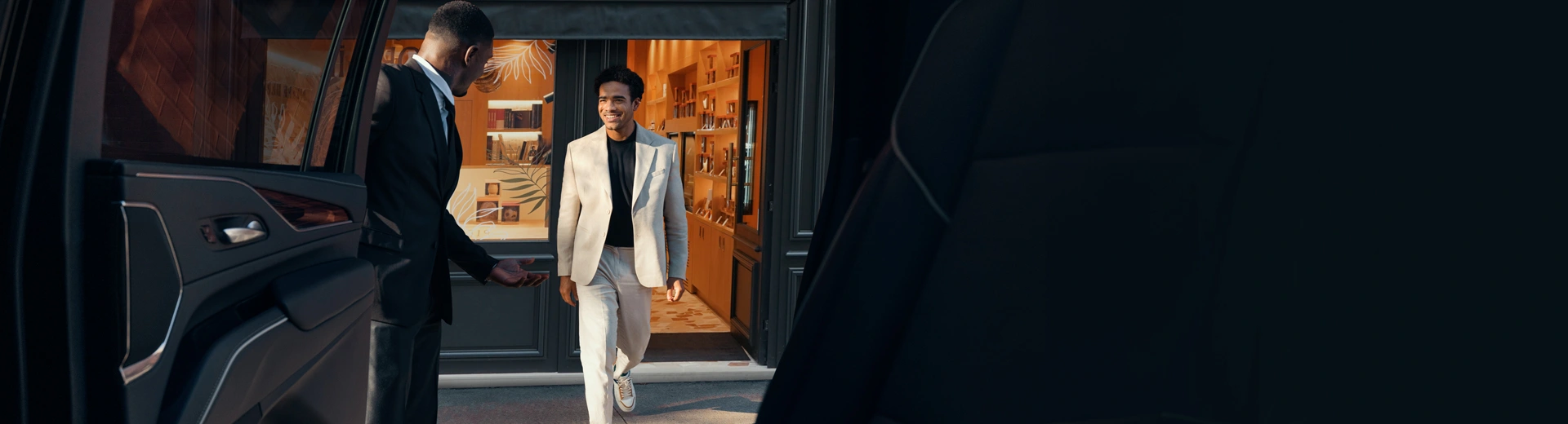 Chauffeur holds the car door open for guest walking towards the vehicle.