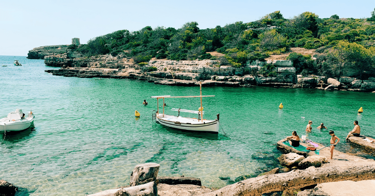 <figcaption class="wp-element-caption">Crystal-clear waters at Cala Alcaufar make this sustainable travel spot a must-visit. <em>Image credit: Laura Velasco/Unsplash</em></figcaption>