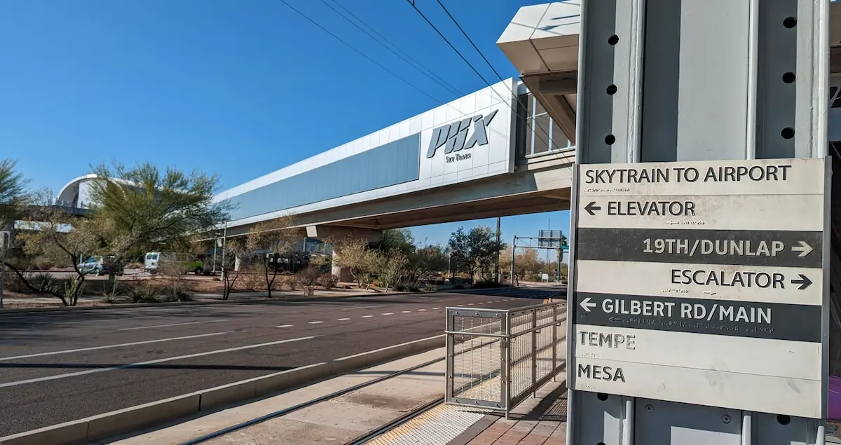 Shot of the Phoenix Airport SkyTrain station above a road, with a signpost in the foreground.