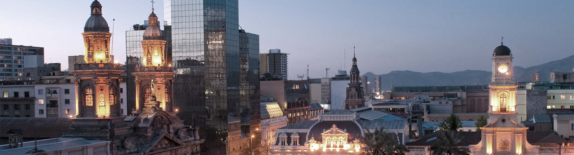 Framed by the Andes mountains in the distance, some of Santiago's more modern buildings surround a colonial-era church.