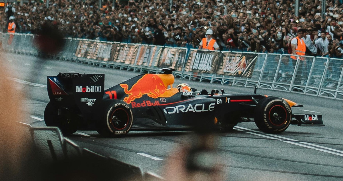 Action shot of a Red Bull F1 car in a spin at a Grand Prix street event, with crowds and marshals behind a barrier in the background.