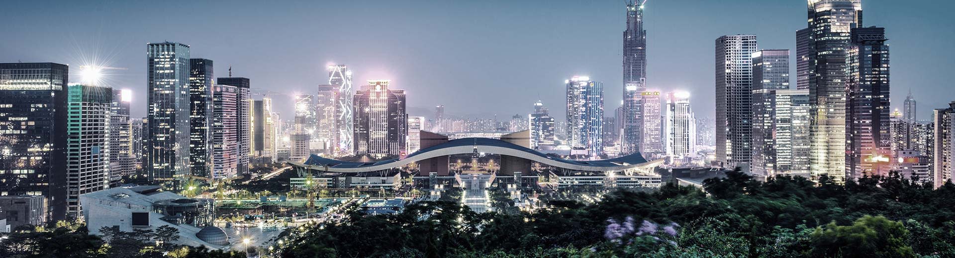 Moderne Gebäude und Wolkenkratzer leuchten den Nachthimmel über Shenzhen.
