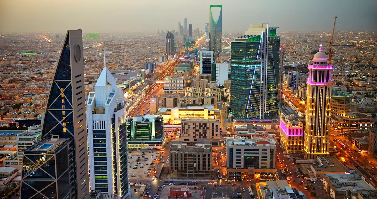Skyscrapers lit up in Riyadh's Al Olaya central business district at dusk.