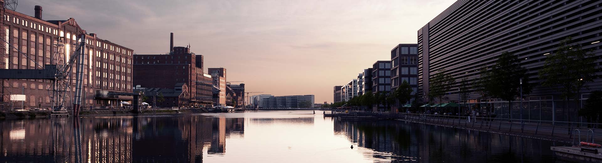 Les anciens bâtiments industriels de Duisburg se sont placés contre un soleil de gradin, avec un canal menant à un horizon lointain.