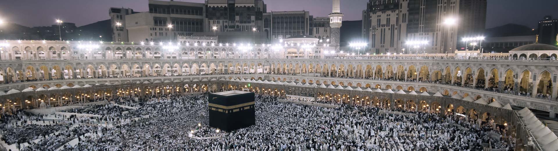 Die berühmte Kaaba in Mekka nachts, umgeben von Anbetern.