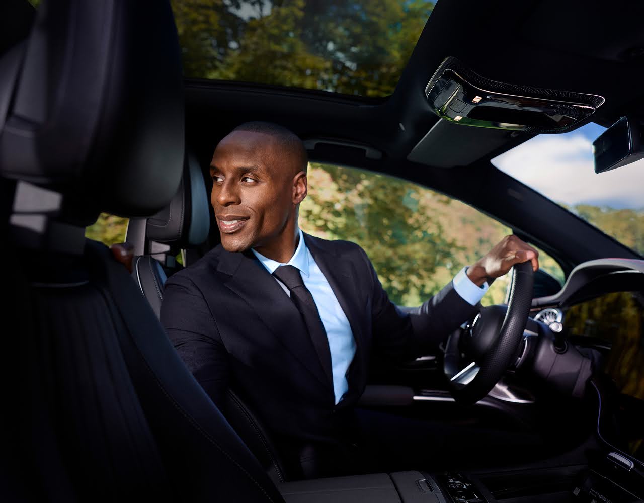 A Blacklane chauffeur turned around in the driver's seat smiling back at his passenger.