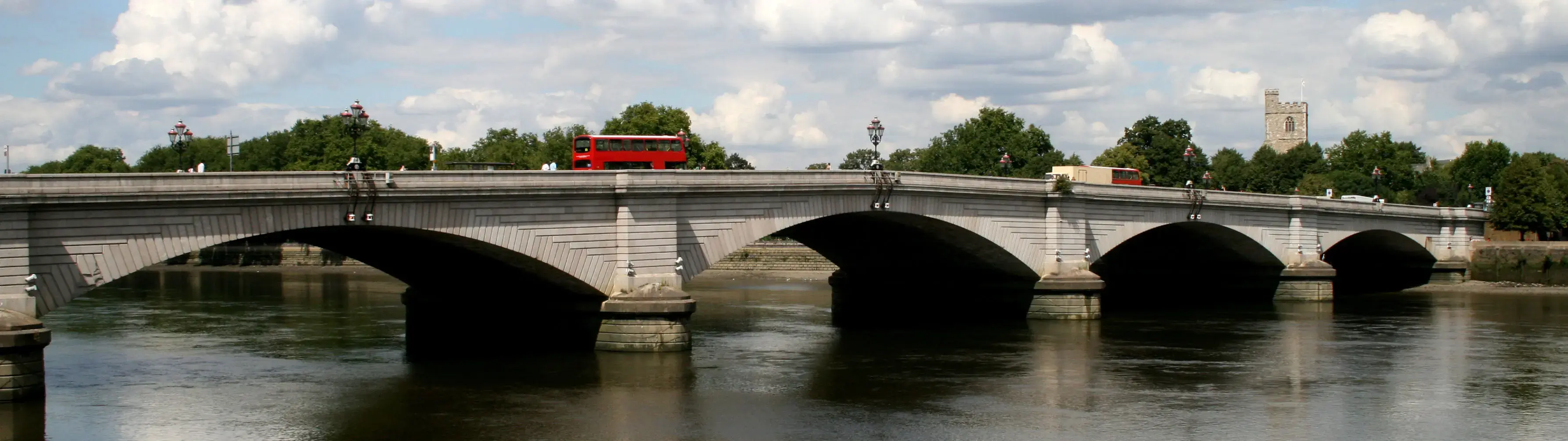  A red London bus crosses the River Thames at Putney Bridge.