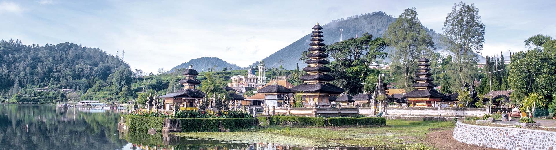 Templo de Ulun Danu Beratan en Bali junto al tranquilo lago Beratan con montañas en el fondo.