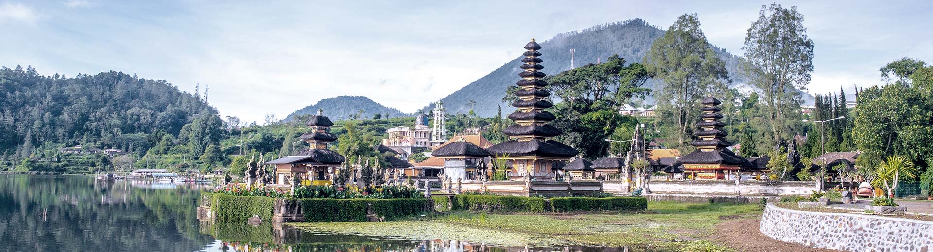 Ulun Danu Beratan Tempel in Bali neben dem ruhigen Beratan -See mit Bergen im Hintergrund.