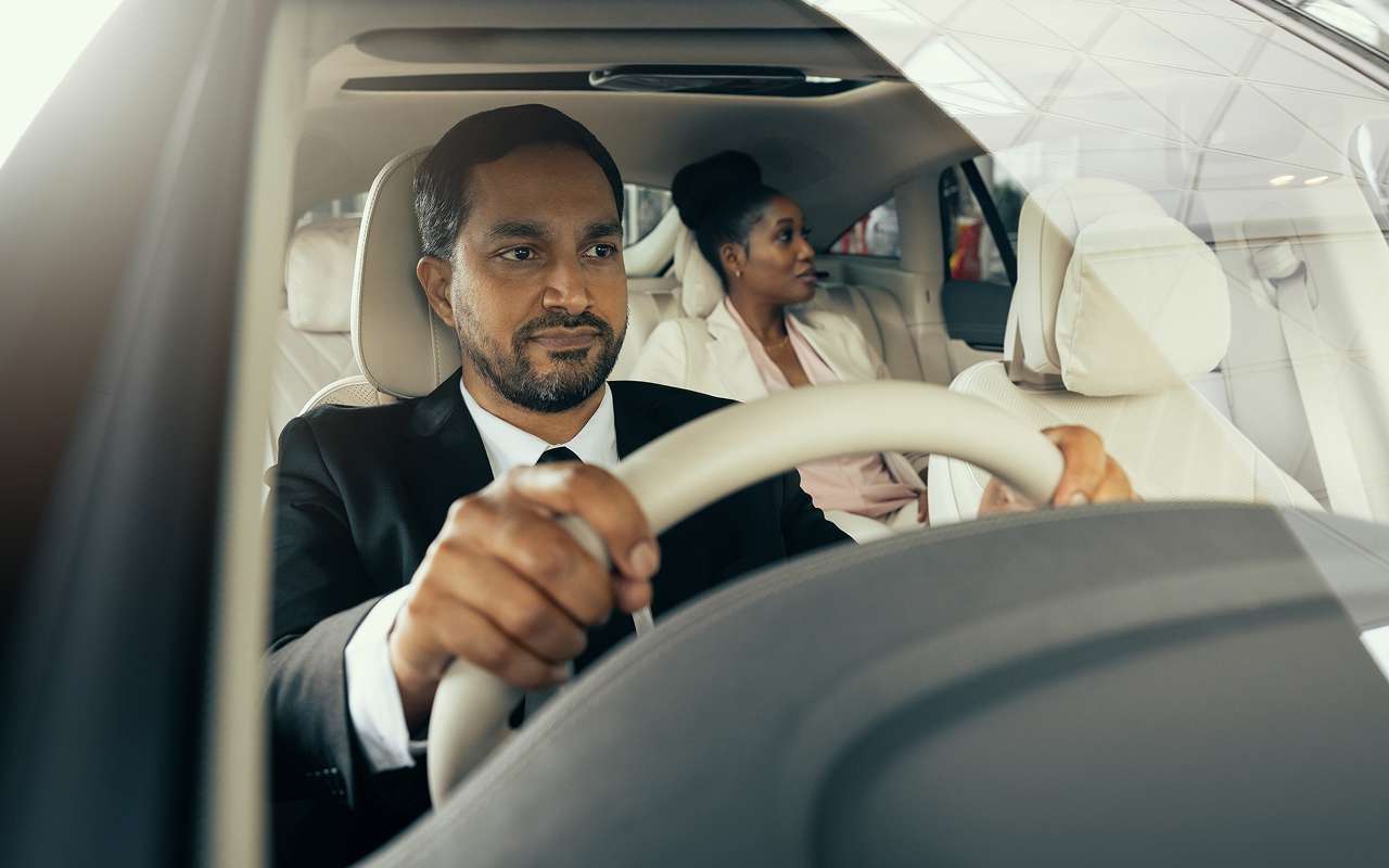 A Blacklane chauffeur behind the wheel of transports a female passenger to a medical appointment.