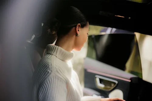 Shot of an elegant woman sitting in the backseat of a Blacklane limousine with the door being held open for her.