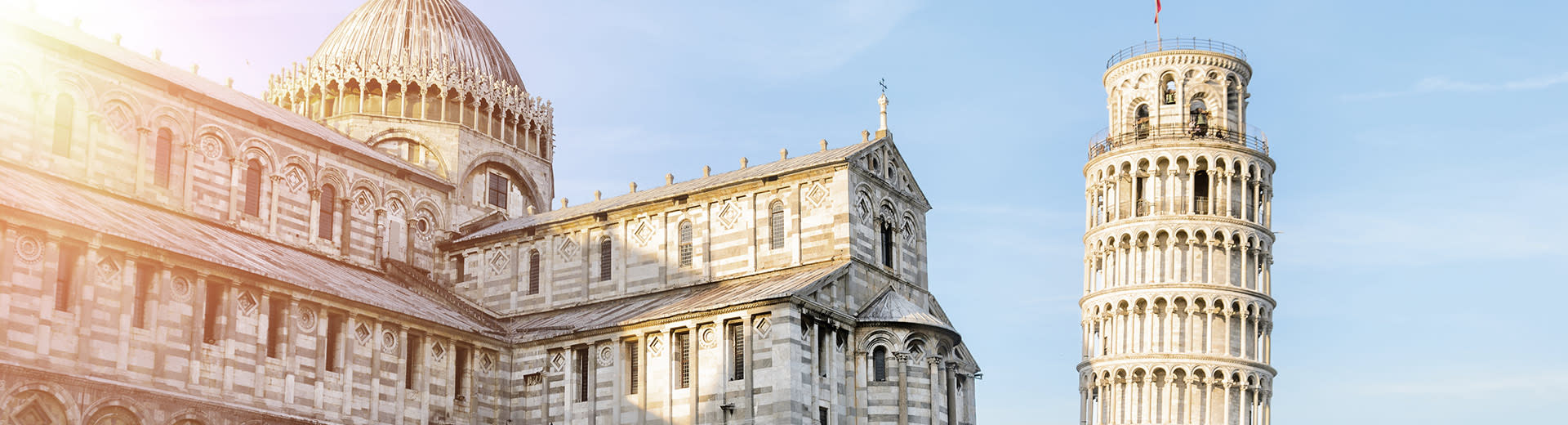 Le soleil brille sur la tour penchée de Pise et la cathédrale voisine.