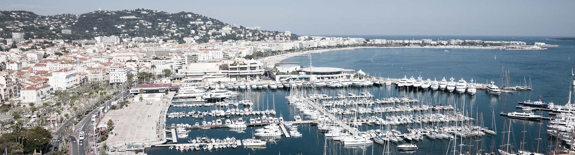 Des bateaux blancs et des bâtiments blancs le long du rivage par une journée claire et ensoleillée à Cannes.