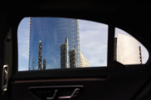 Shot of glass skyscrapers through the back window of a luxury car.