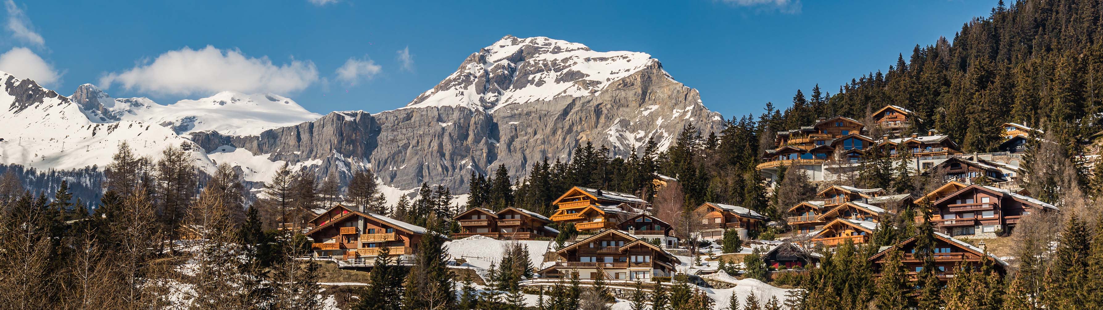 Chalets lie before the imposing mountain peak of Crans Montana.