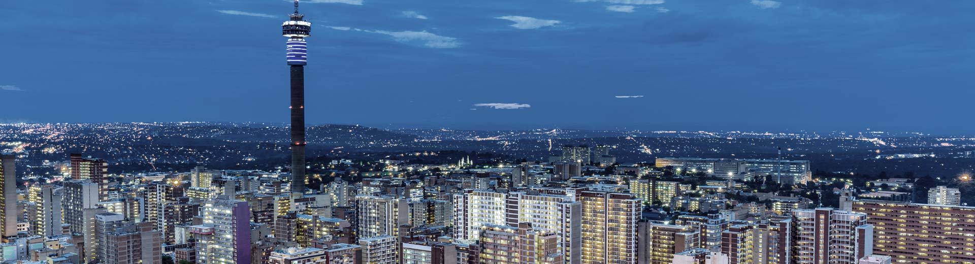 El brillante horizonte Johannesburgo en una noche oscura, con edificios de oficinas de gran altura y unidades residenciales.