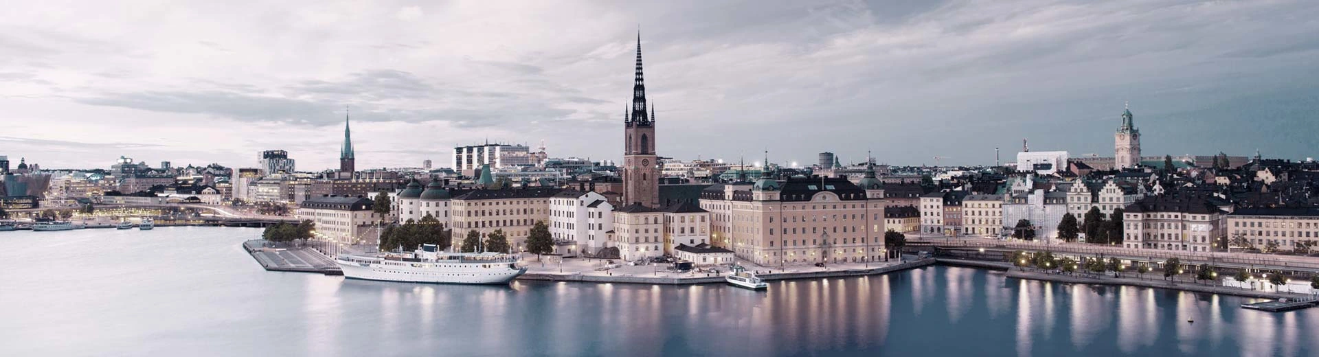Historische Gebäude säumen die Ufer von Stockholm mit Grauhimmelkirchenstürmen und moderneren Gebäuden.