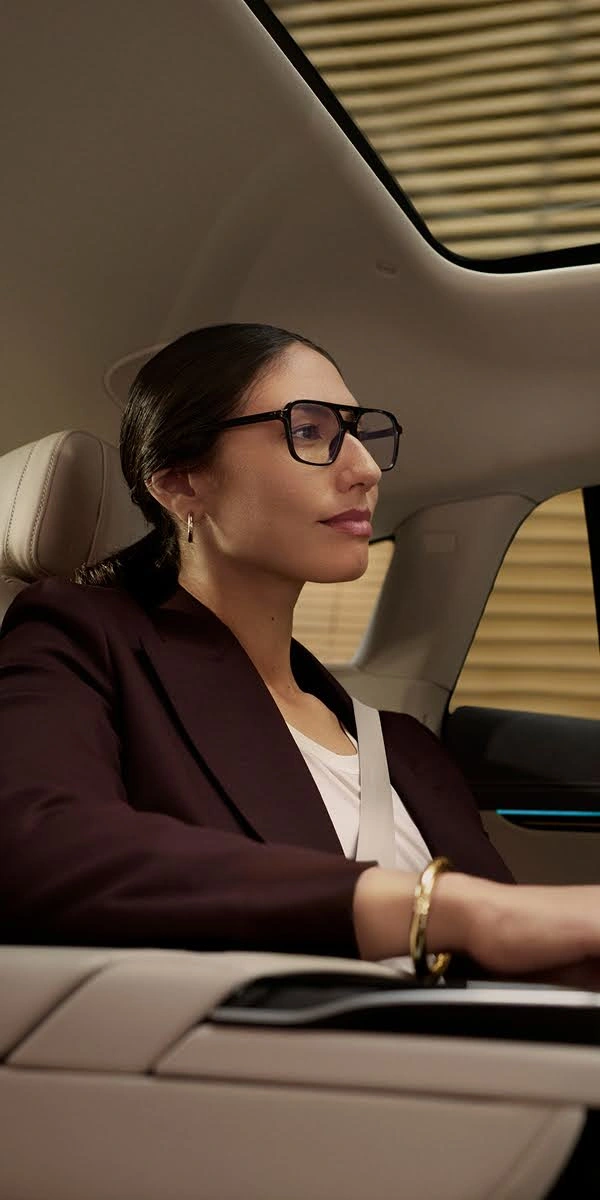 A smartly dressed woman with designer glasses sits in the backseat of a Blacklane limousine.