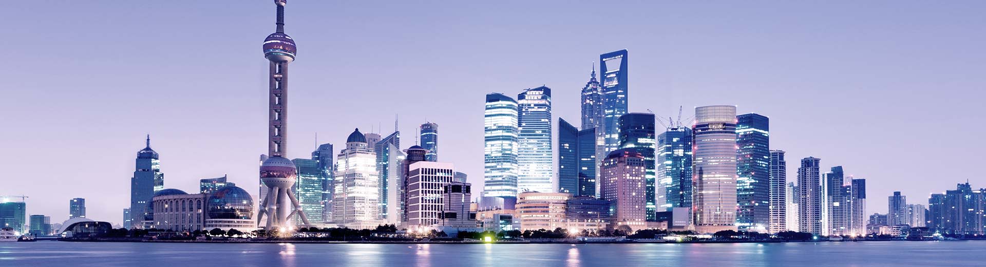 Die Skyline von Shanghai brogt mit einer Vielzahl moderner und hoch aufragender Skyraper im Halblicht der Dämmerung.