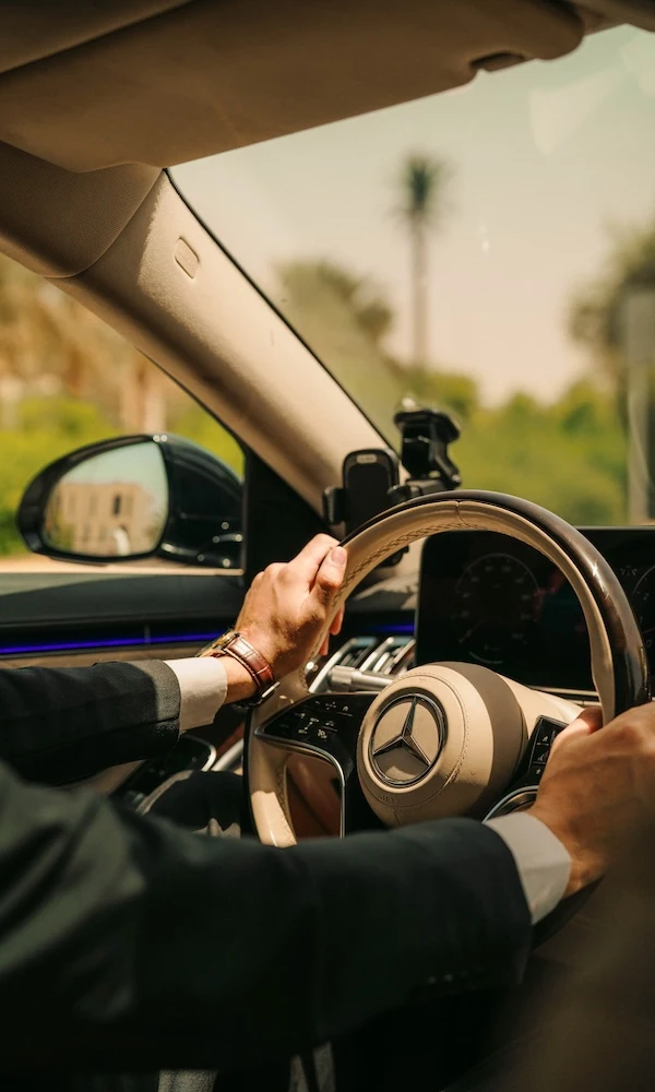 A chauffeur's hands on a Mercedes EQS steering wheel.