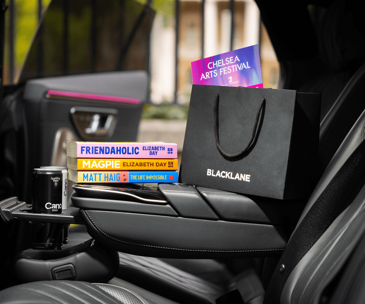 The Chelsea Curated goody bag from shot inside a Blacklane limo, and a pile of books.