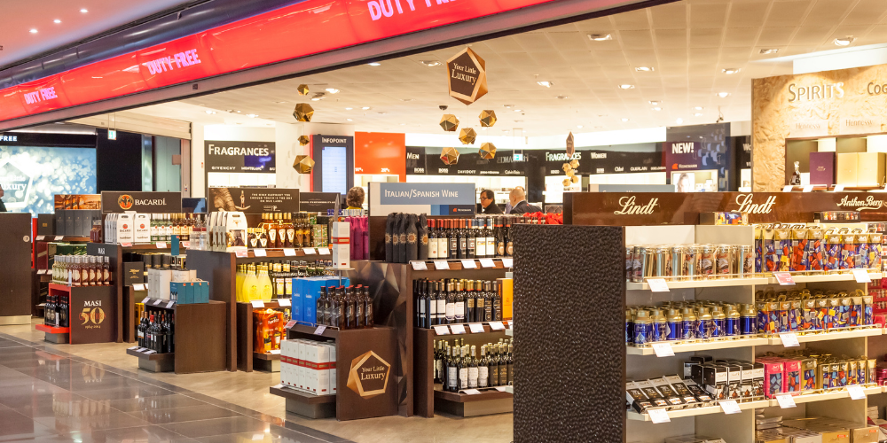 Spacious duty free shopping area with a wide selection of spirits, chocolates, and fragrances, prominently featuring Lindt and Bacardi displays.