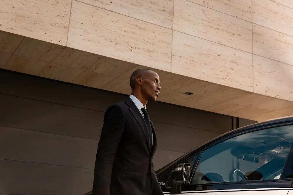 A Blacklane chauffeur walks to the side of a car.