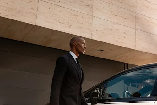 A Blacklane chauffeur walks to the side of a car.