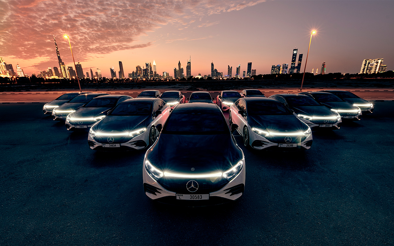 Mercedes-Benz EQSes parked in from of the Dubai skyline at sunset.