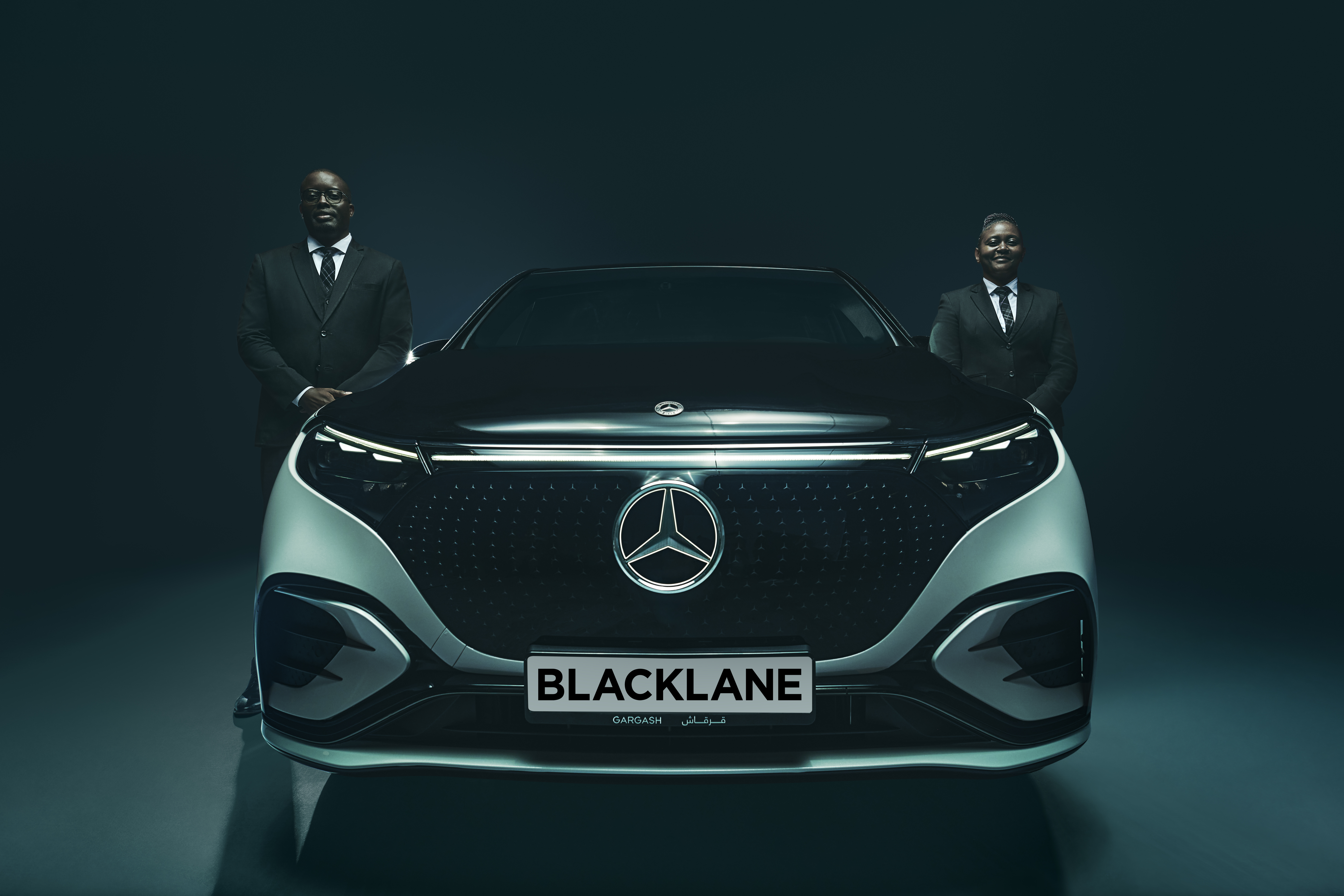 Zwei Chauffeure stehen auf jeder Seite eines zweifarbigen Mercedes EQS.