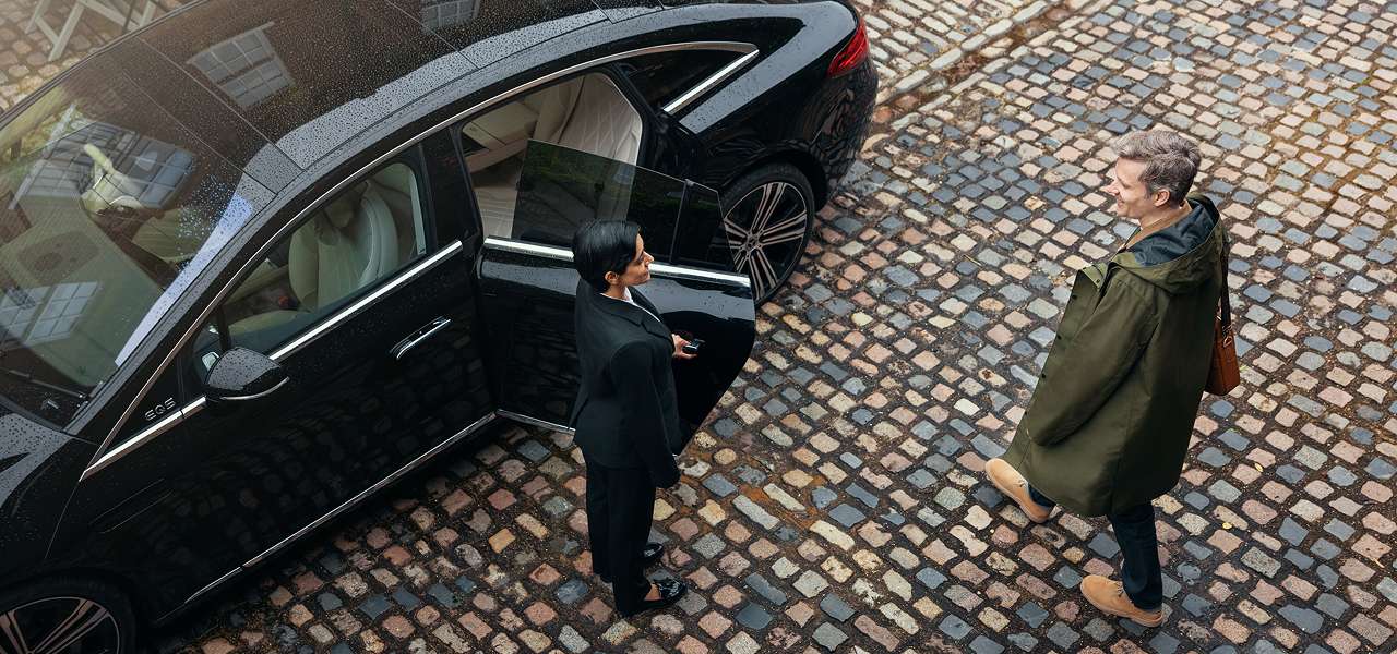 A Blacklane chauffeur holds the door of a limo open for a doctor on his way to work.