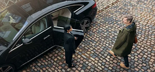 A Blacklane chauffeur holds the door of a limo open for a doctor on his way to work.