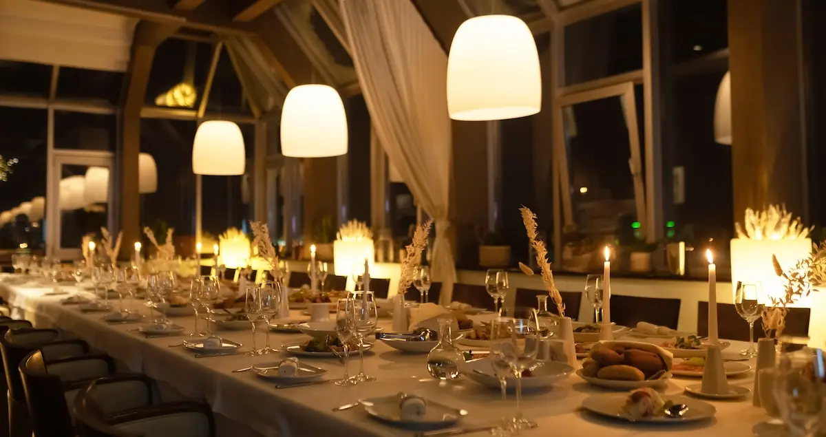 A beautifully arranged long dining table with candles and soft lighting, perfect for a private dining event.