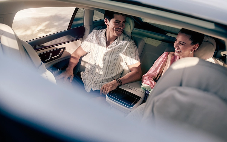 Shot through the sunroof into the backseat of a Blacklane limo as a smiling couple sit there.