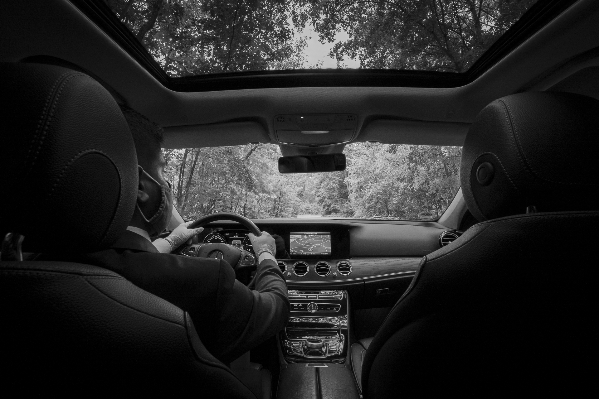 Male chauffeur driving with mask, backseat view