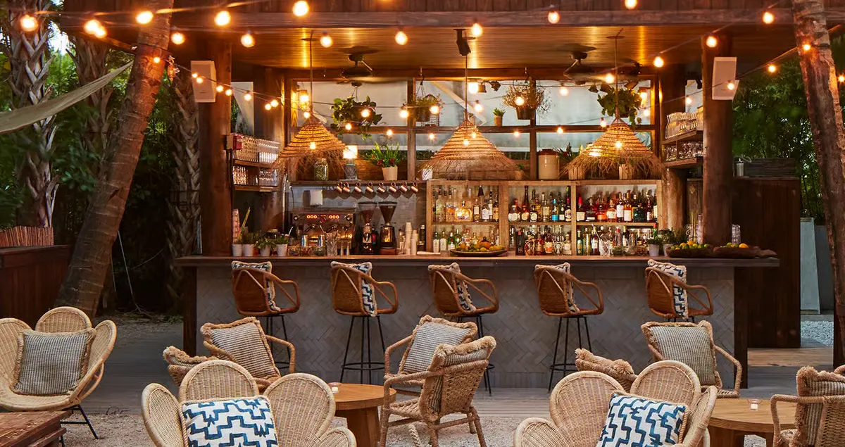 A shot of the beachside bar at Soho Beach House Miami, showing soft lighting and beach chairs.