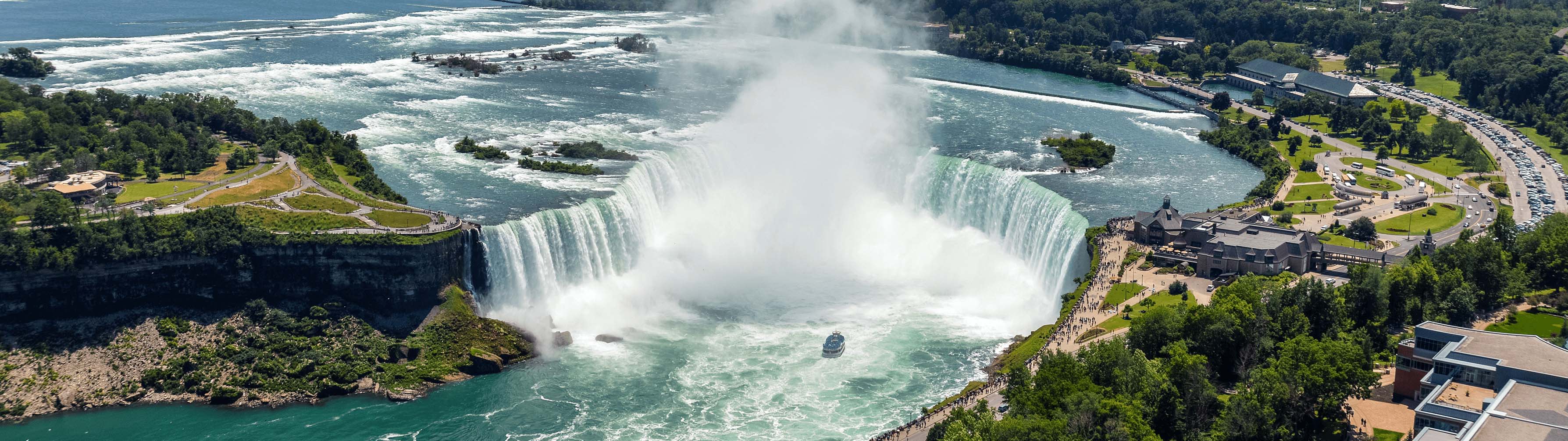 The iconic waters of Niagara Falls on a clear, warm day.