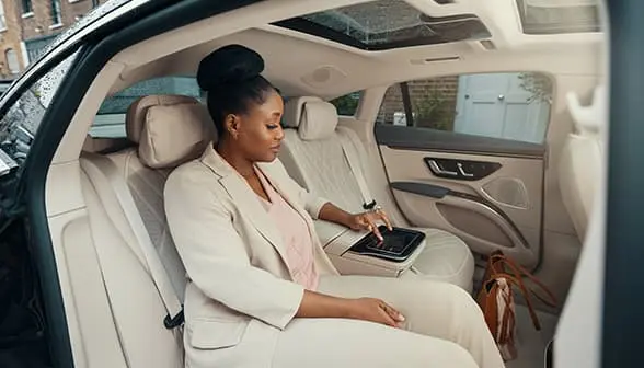 A businesswoman sits in the back seat of a Blacklane first class limo.