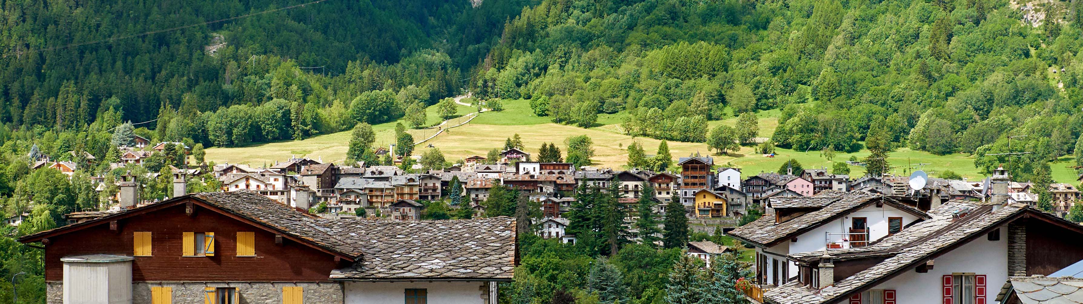 On a summer's day, the chalets and cabins of Chamonix lie before rolling green slopes.