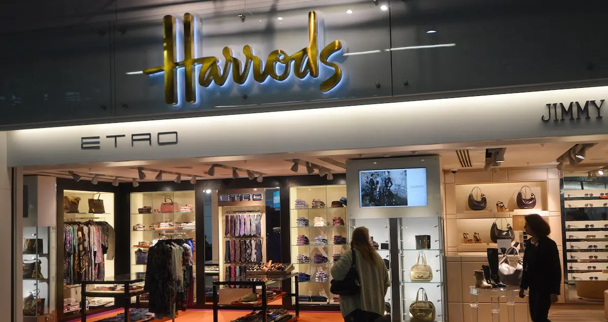Passengers passing Harrods department store at Heathrow Airport Terminal 4 departure lounge which sells a wide range of luxury brands.