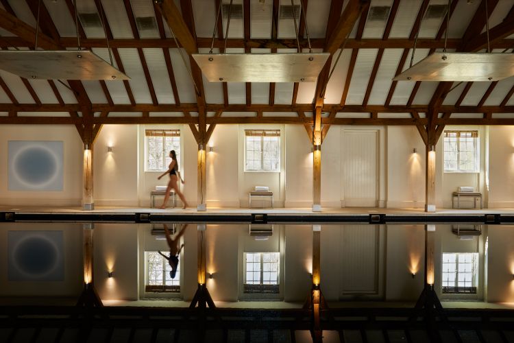 A woman walks past the atmospherically-lit swimming pool in the Sequoia Spa at The Grove hotel.