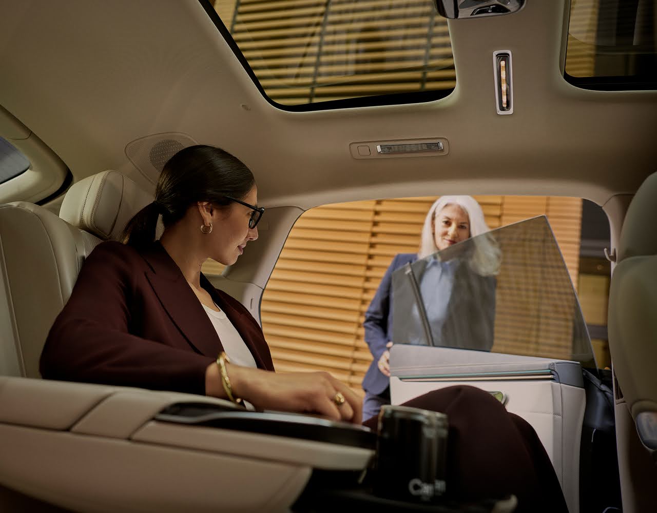 A businesswoman gets out a Blacklane limo at an airport while a chauffeur holds the door.