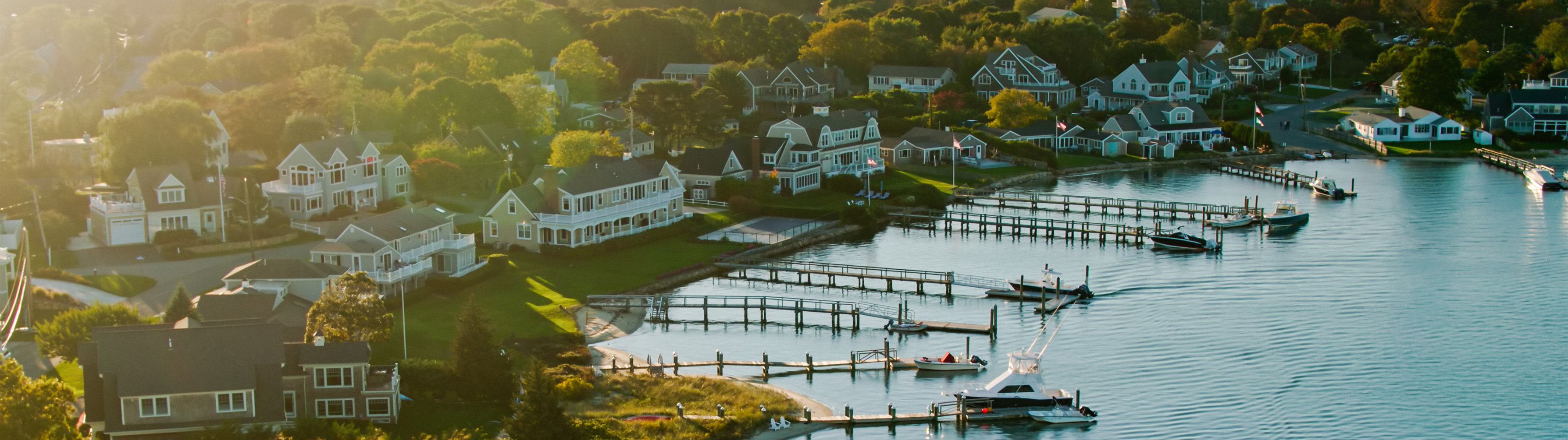 Beautiful Cape Cod, seemingly old houses sit next to a pristene body of water.