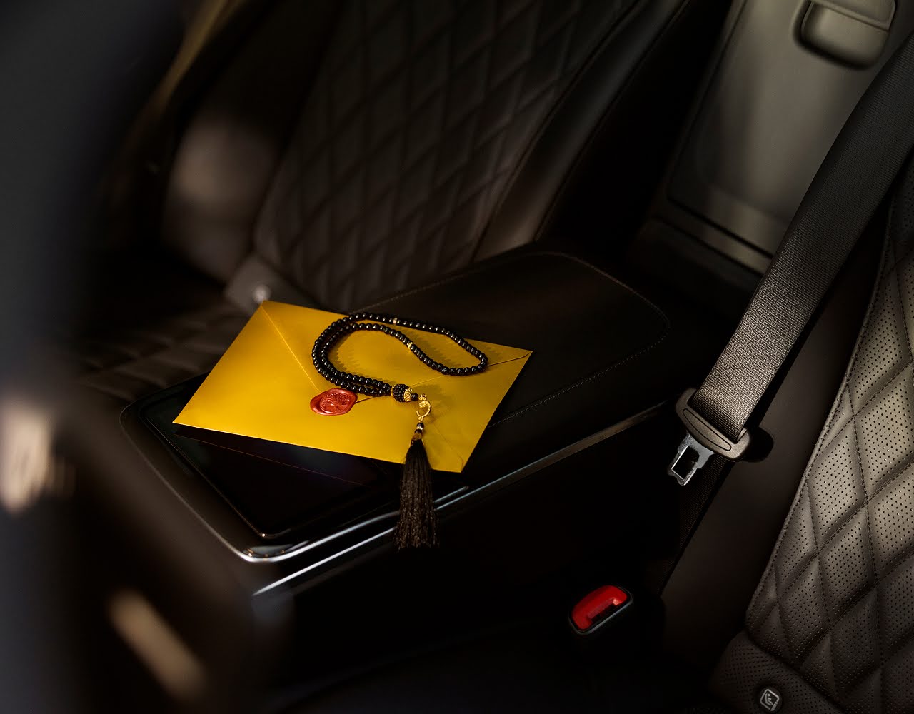Some prayer beads in the back seat of a luxury car.