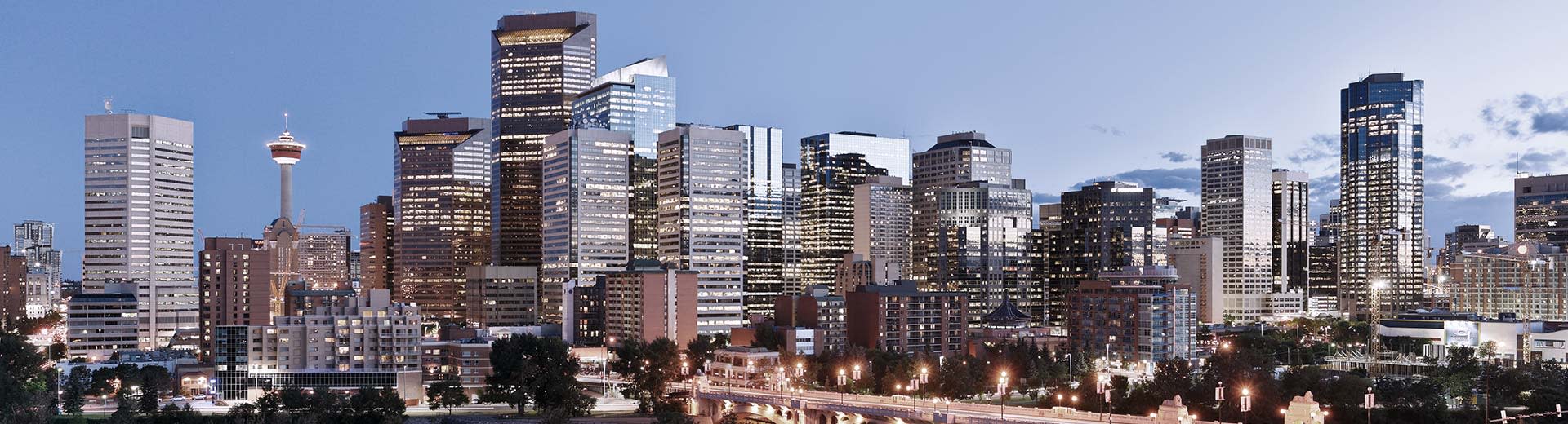 The imposing skyline of Calgary lights up the sky during sunset.