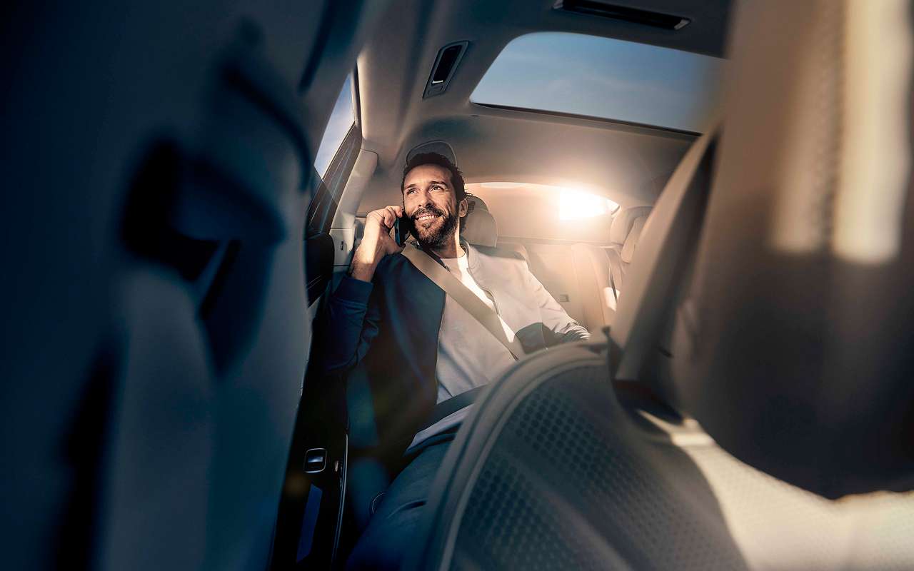 A businessman sits in the back seat of a Blacklane limo having a phonecall.
