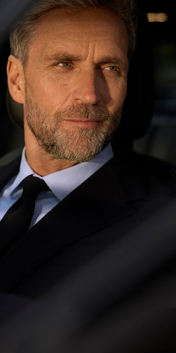 Un chofer espera paitadamente por un auto elegante.